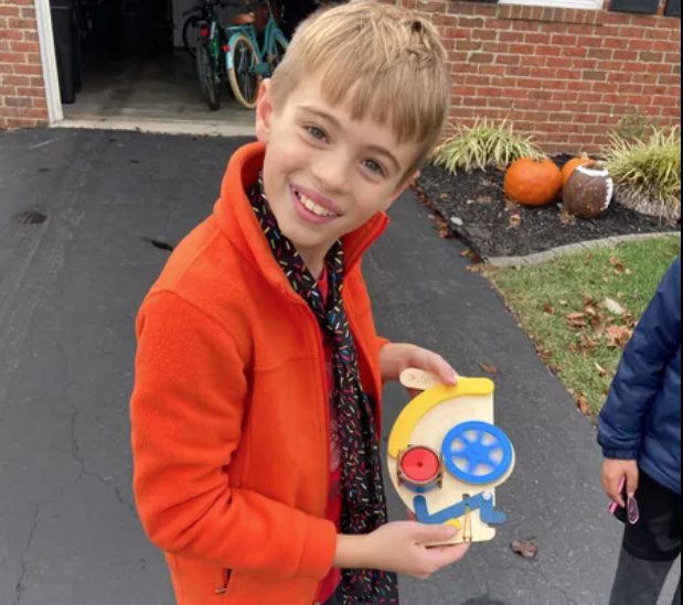 Photo of a Boy Playing with a Build Box in the Street